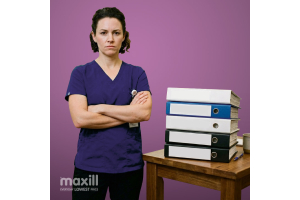 Dental professional with arms crossed beside a table with a stack of binders